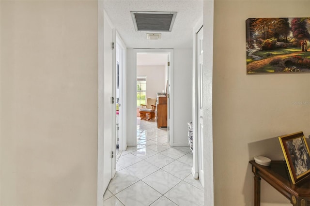 hallway with light tile flooring and a textured ceiling