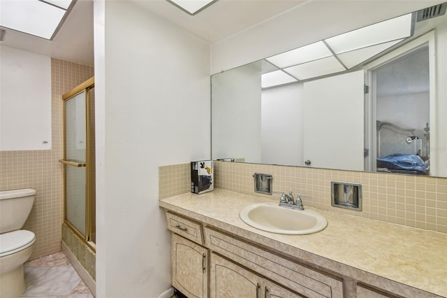 bathroom with tile flooring, tile walls, tasteful backsplash, large vanity, and toilet