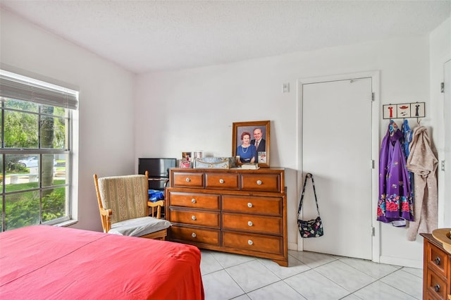 bedroom featuring a textured ceiling, light tile floors, and multiple windows