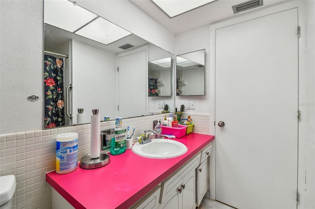 bathroom featuring vanity with extensive cabinet space, tile walls, toilet, and tasteful backsplash