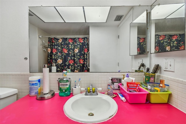 bathroom featuring sink, tasteful backsplash, toilet, and tile walls