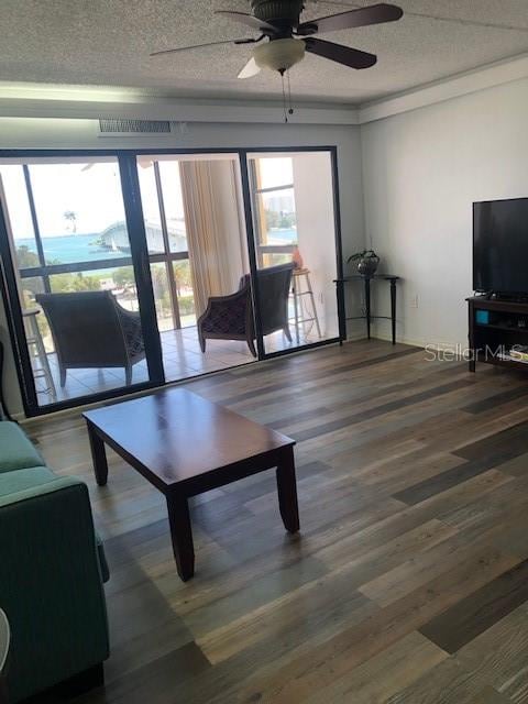 living room featuring hardwood / wood-style floors, ceiling fan, and a textured ceiling