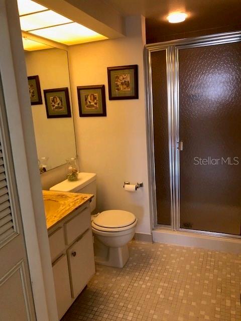 bathroom with vanity, toilet, walk in shower, and tile patterned flooring