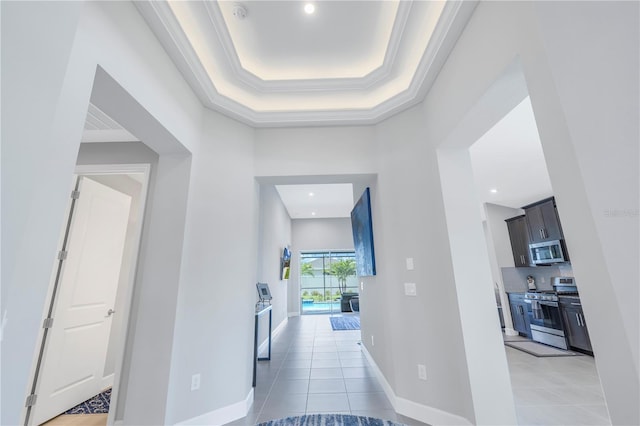 hall featuring a high ceiling, crown molding, a raised ceiling, and light tile patterned flooring