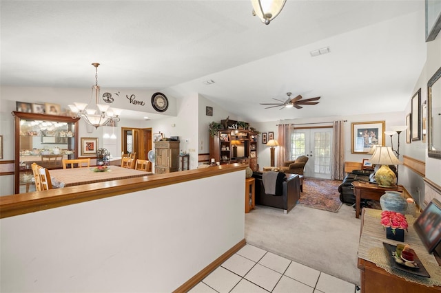 carpeted living room featuring ceiling fan with notable chandelier, french doors, and vaulted ceiling