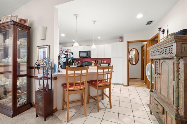 kitchen with pendant lighting, black appliances, white cabinets, light tile patterned floors, and kitchen peninsula