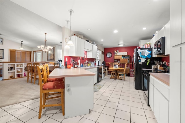 kitchen with pendant lighting, stainless steel range with electric cooktop, white cabinetry, a kitchen bar, and kitchen peninsula