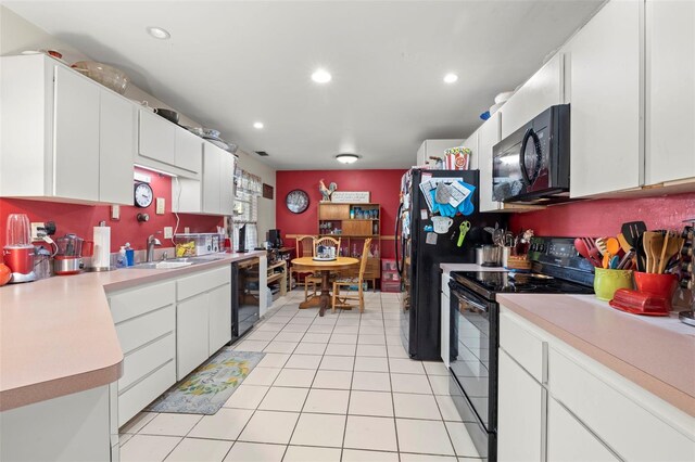 kitchen featuring black appliances, white cabinetry, sink, and light tile patterned floors