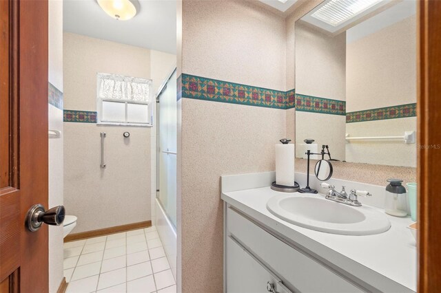 full bathroom with tile patterned floors, vanity, bath / shower combo with glass door, and toilet