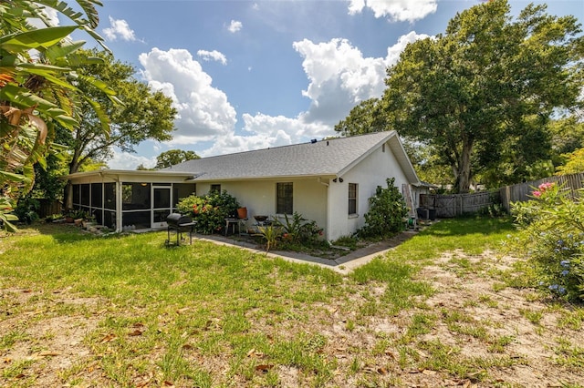 rear view of property featuring a yard, central AC unit, and a sunroom