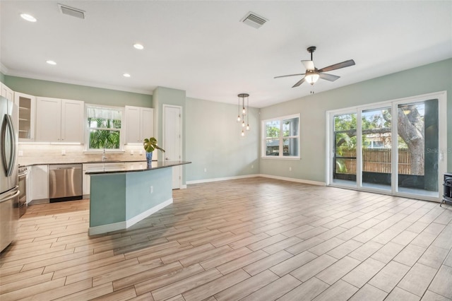 kitchen featuring white cabinetry, hanging light fixtures, ceiling fan, stainless steel appliances, and backsplash