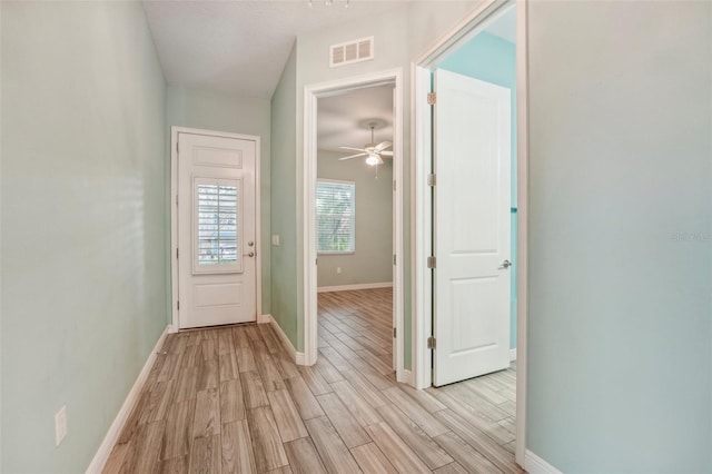 doorway to outside featuring light wood finished floors, a ceiling fan, visible vents, and baseboards