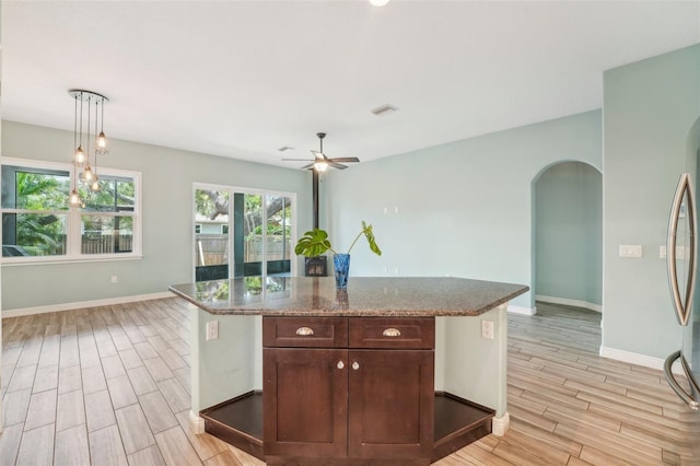 kitchen with arched walkways, dark brown cabinets, a ceiling fan, and wood finish floors