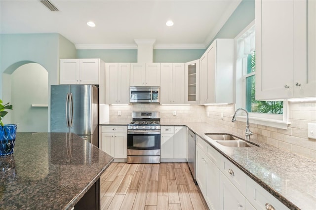 kitchen with stainless steel appliances, a sink, visible vents, tasteful backsplash, and dark stone countertops