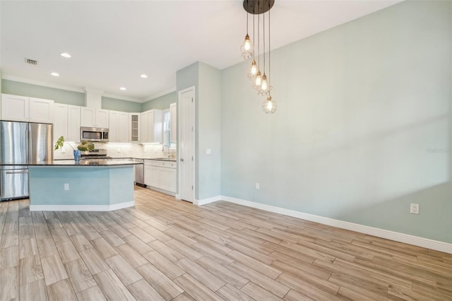 kitchen featuring stainless steel appliances, visible vents, white cabinetry, light wood-type flooring, and tasteful backsplash