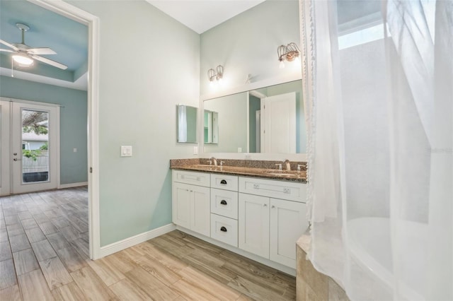 bathroom with double vanity, baseboards, ceiling fan, wood finished floors, and a sink