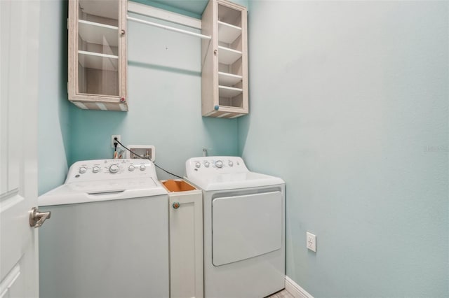 clothes washing area featuring laundry area, baseboards, and washer and dryer