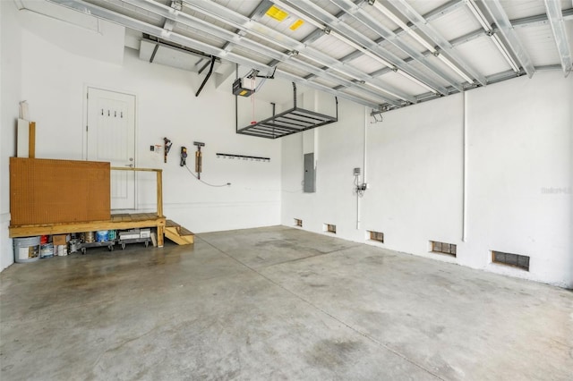 garage featuring visible vents, electric panel, and a garage door opener