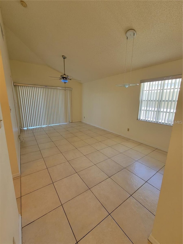 tiled empty room with a textured ceiling, ceiling fan, and vaulted ceiling