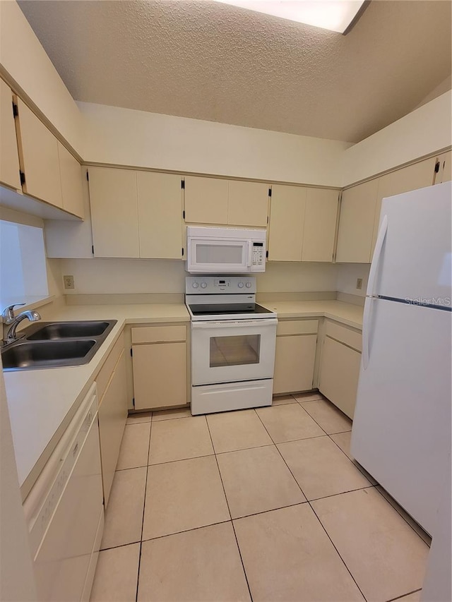 kitchen with cream cabinets, sink, and white appliances