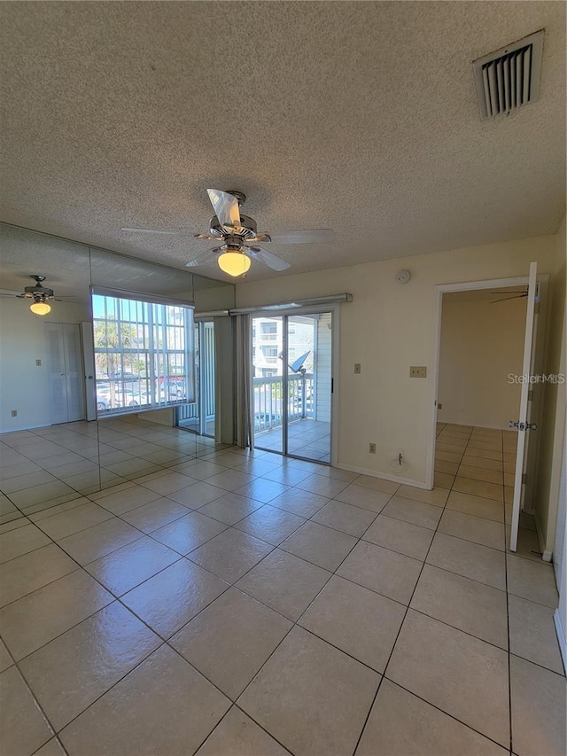 tiled empty room with a textured ceiling and ceiling fan