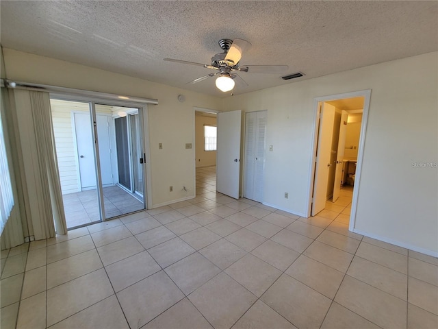 unfurnished bedroom with ceiling fan, light tile patterned flooring, a textured ceiling, and a closet