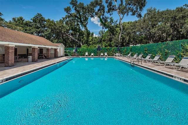 pool with a patio area and fence