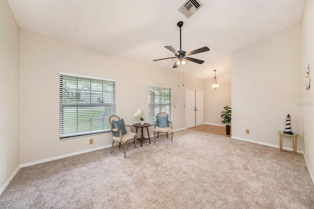 living area featuring lofted ceiling, visible vents, a ceiling fan, carpet flooring, and baseboards