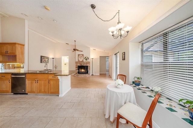 kitchen featuring dishwasher, lofted ceiling, open floor plan, a fireplace, and a sink