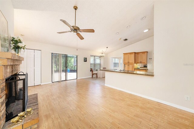 unfurnished living room with baseboards, ceiling fan with notable chandelier, light wood-type flooring, a fireplace, and recessed lighting