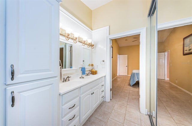 bathroom with tile patterned floors, a sink, baseboards, and double vanity