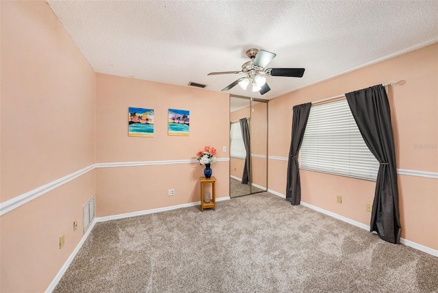 carpeted spare room with visible vents, a textured ceiling, and baseboards