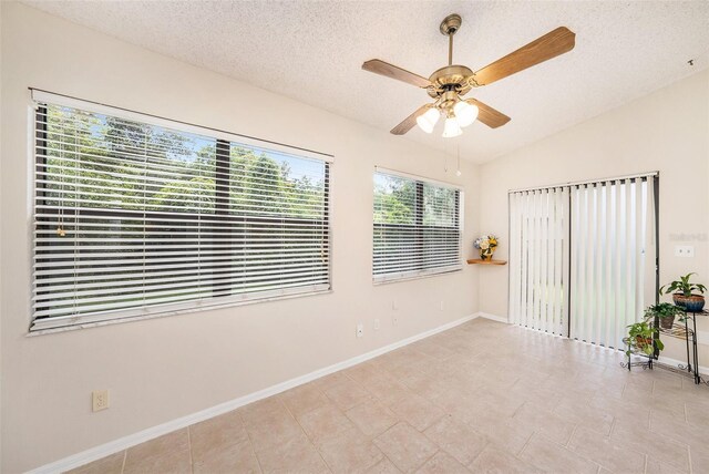 spare room featuring lofted ceiling, a textured ceiling, a ceiling fan, and baseboards