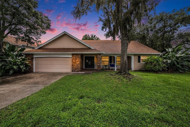 single story home with a garage, concrete driveway, roof with shingles, a yard, and brick siding