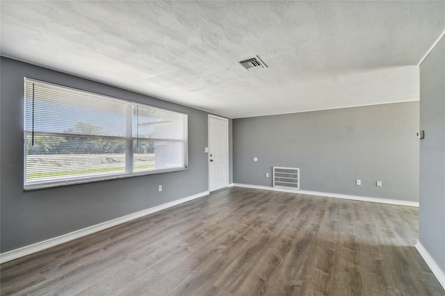 unfurnished room with wood-type flooring, a textured ceiling, and a healthy amount of sunlight