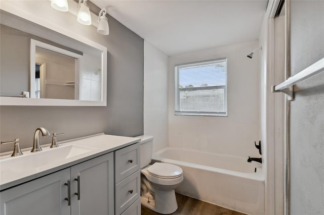 full bathroom featuring vanity, wood-type flooring, tiled shower / bath combo, and toilet