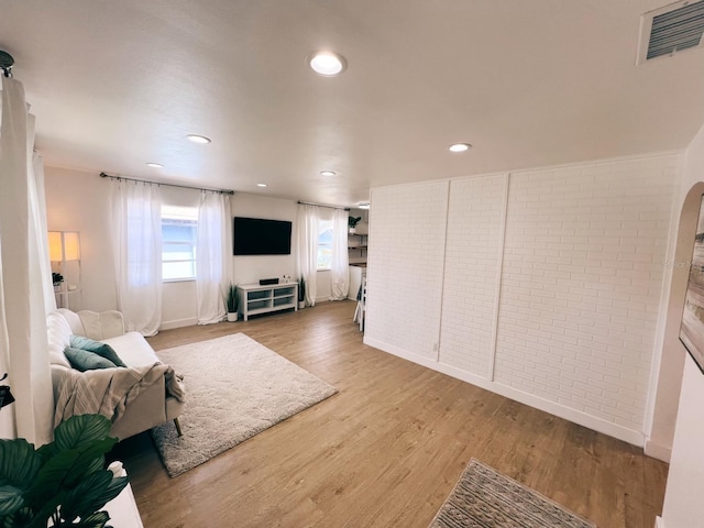 living room with brick wall and hardwood / wood-style floors