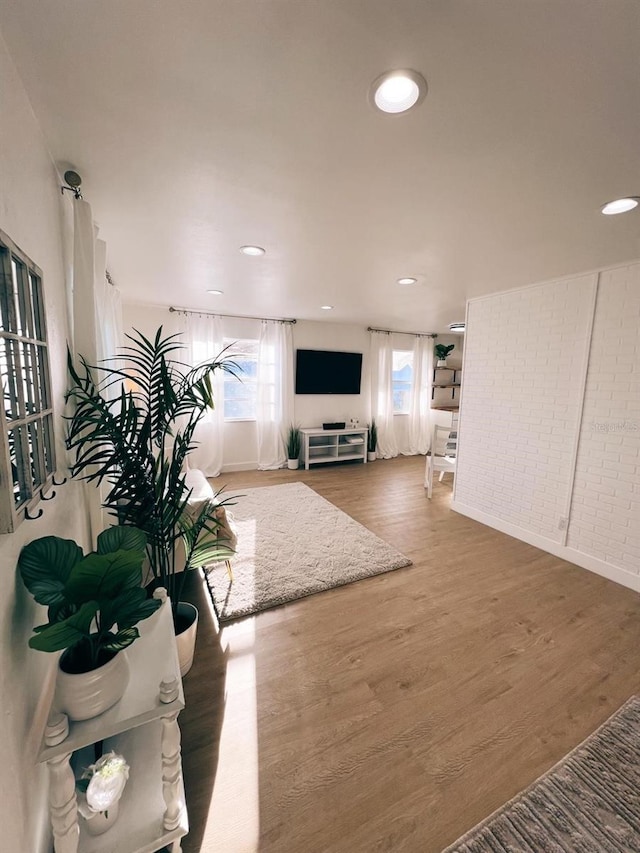 living room featuring hardwood / wood-style flooring and brick wall