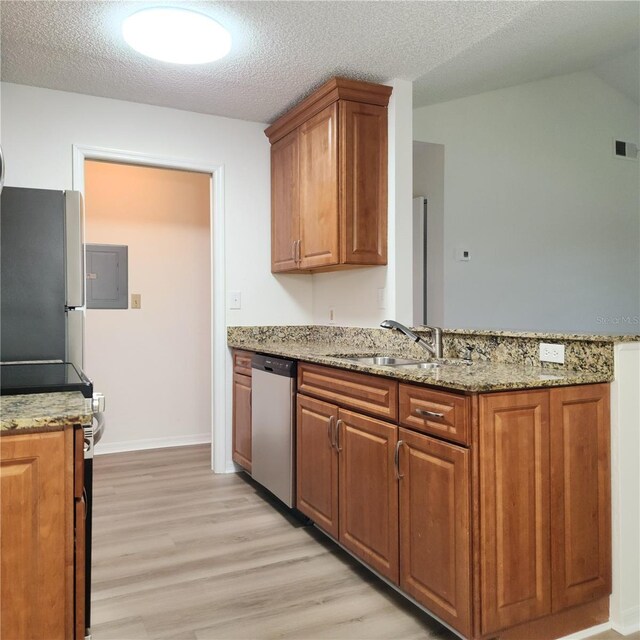 kitchen with sink, light stone counters, electric panel, stainless steel appliances, and light hardwood / wood-style floors