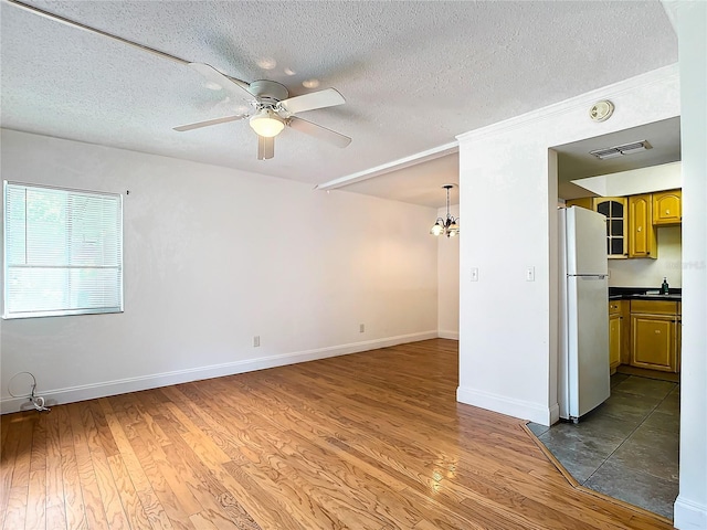 unfurnished living room featuring sink, ceiling fan with notable chandelier, dark wood-type flooring, and a textured ceiling