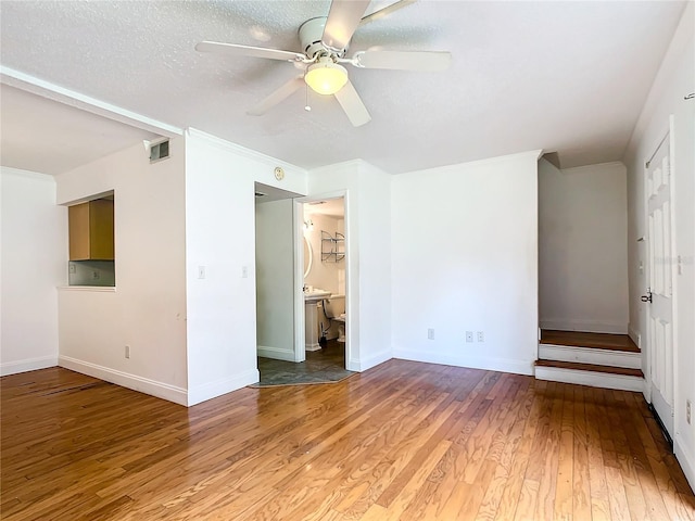 unfurnished bedroom featuring connected bathroom, ceiling fan, hardwood / wood-style floors, and a textured ceiling