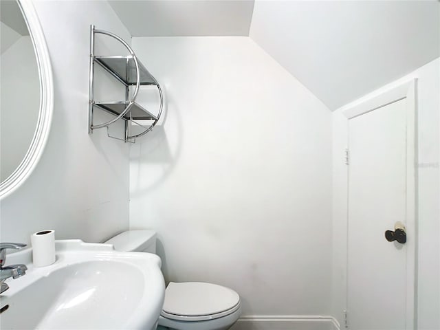 bathroom featuring toilet, lofted ceiling, and sink