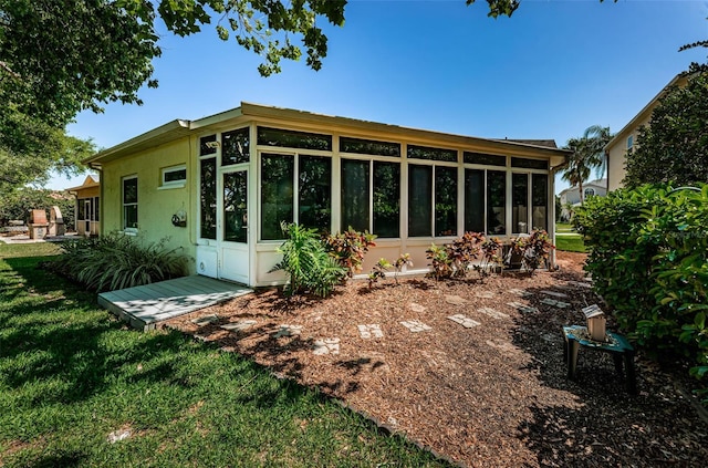 back of house featuring a sunroom and a lawn