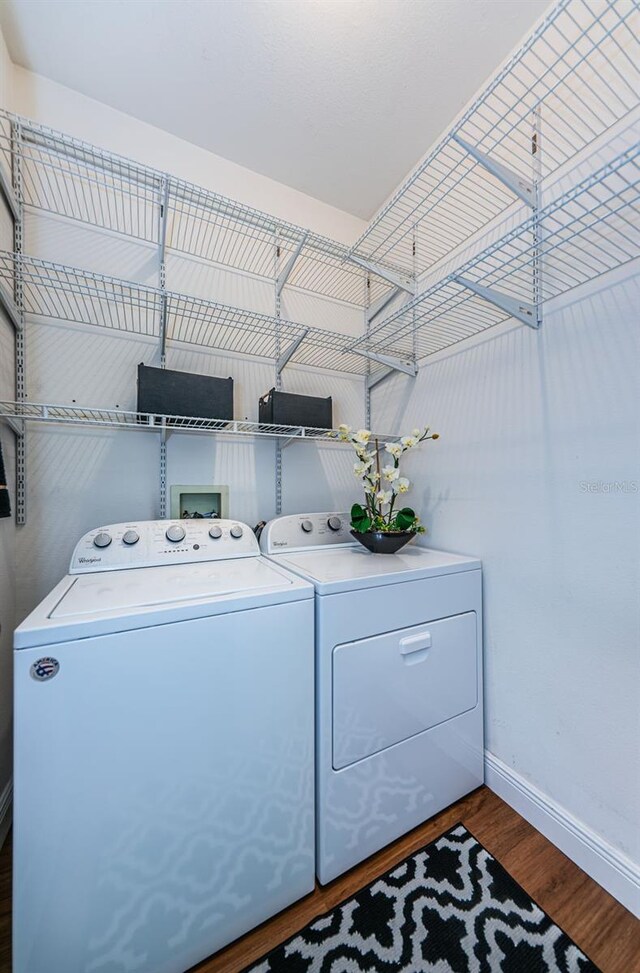 washroom with dark hardwood / wood-style floors and washing machine and dryer