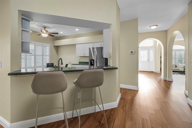 kitchen featuring kitchen peninsula, white cabinetry, a breakfast bar, and stainless steel refrigerator with ice dispenser