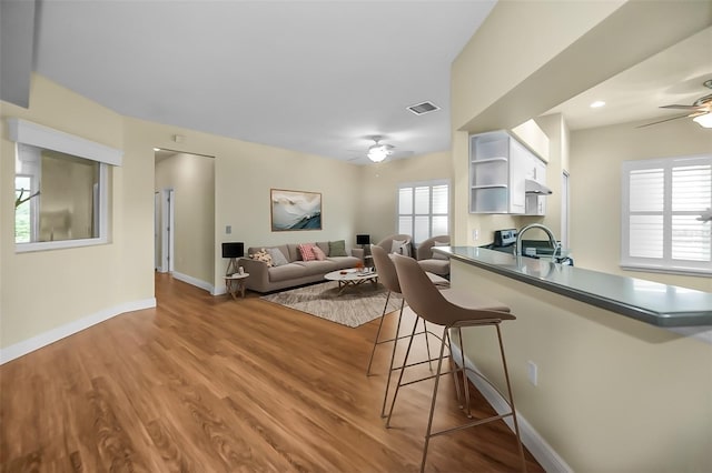 kitchen with white cabinets, sink, hardwood / wood-style flooring, ceiling fan, and kitchen peninsula