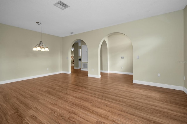 spare room featuring a chandelier and hardwood / wood-style flooring