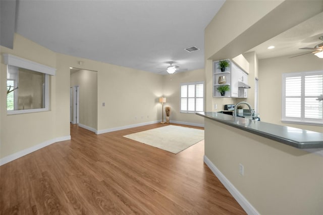 unfurnished living room featuring light hardwood / wood-style floors, ceiling fan, and sink