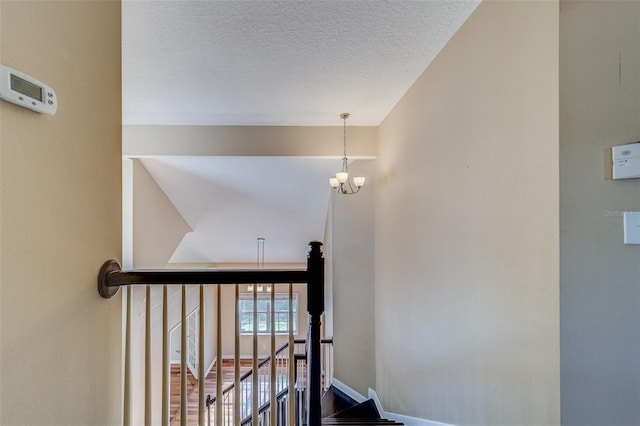 stairway with a textured ceiling and a notable chandelier