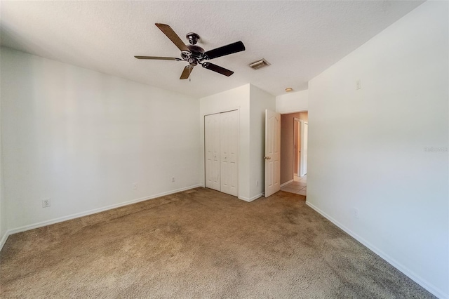 unfurnished bedroom with ceiling fan, carpet floors, a textured ceiling, and a closet